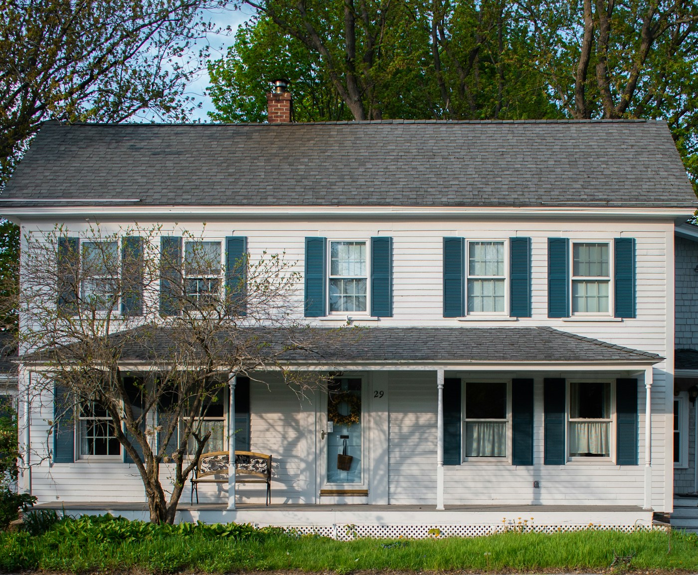 A white home with blue shutters and a welcoming front porch